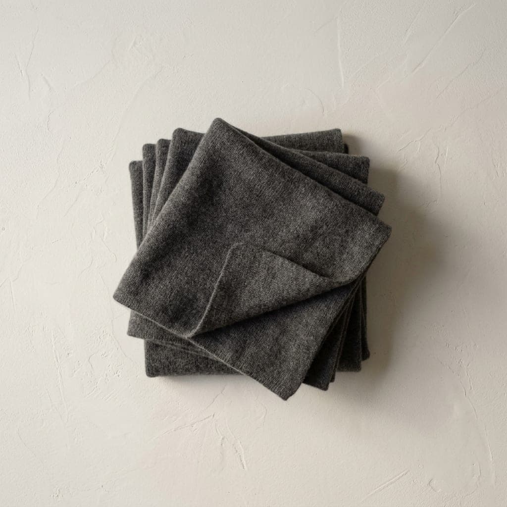 Folded squares of cashmere knit in deep charcoal grey