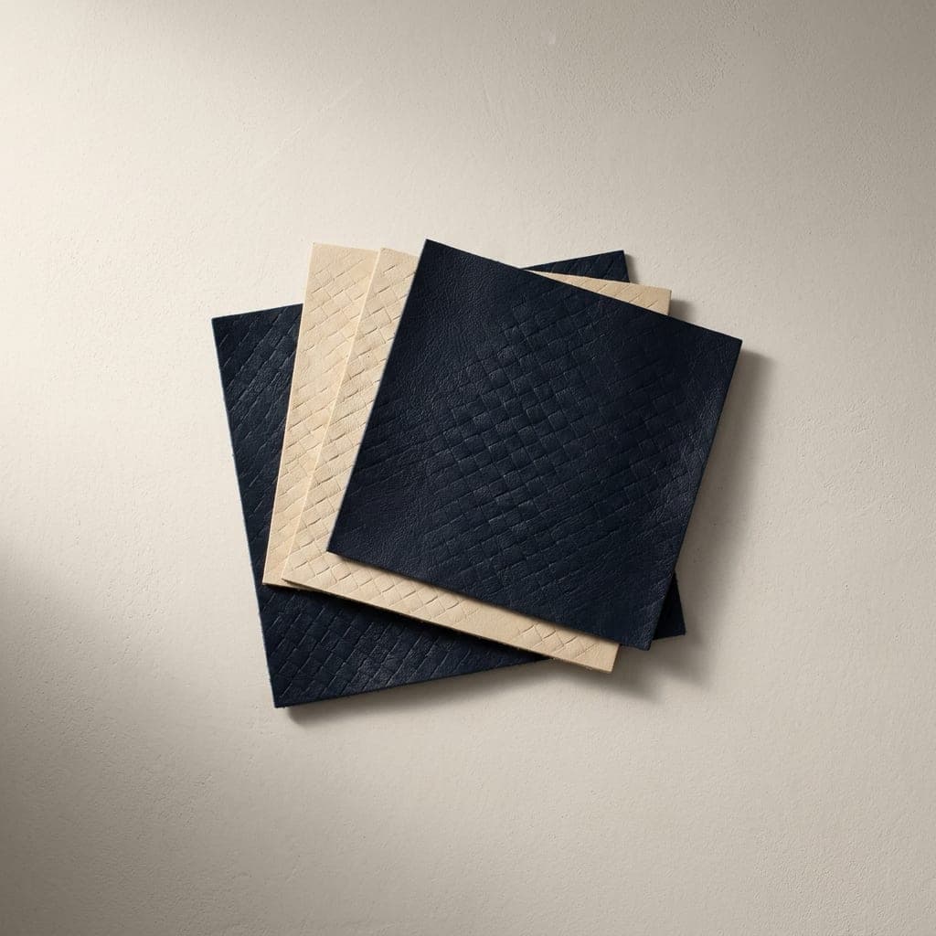 Folded squares of leather in deep navy and warm cream with a woven pattern