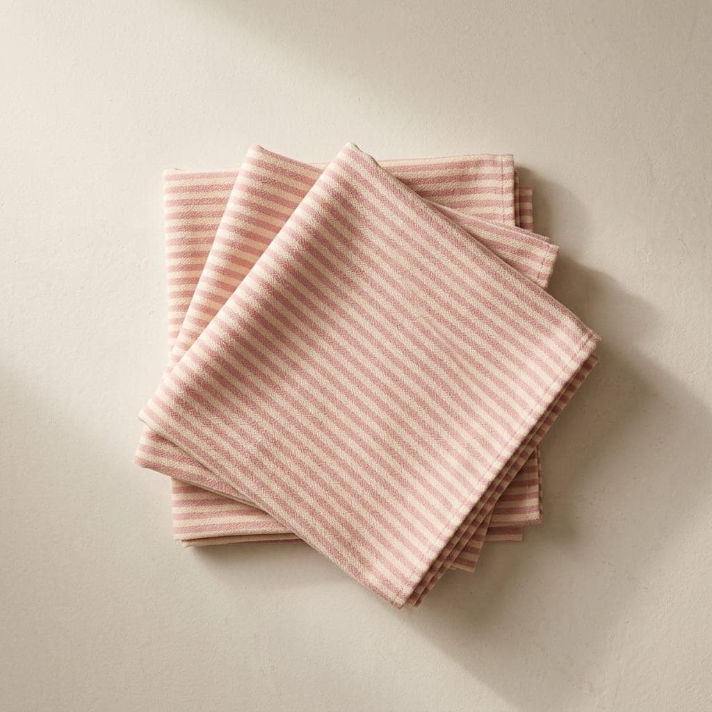 Folded squares of matte crepe in soft rose pink and warm cream in narrow stripes