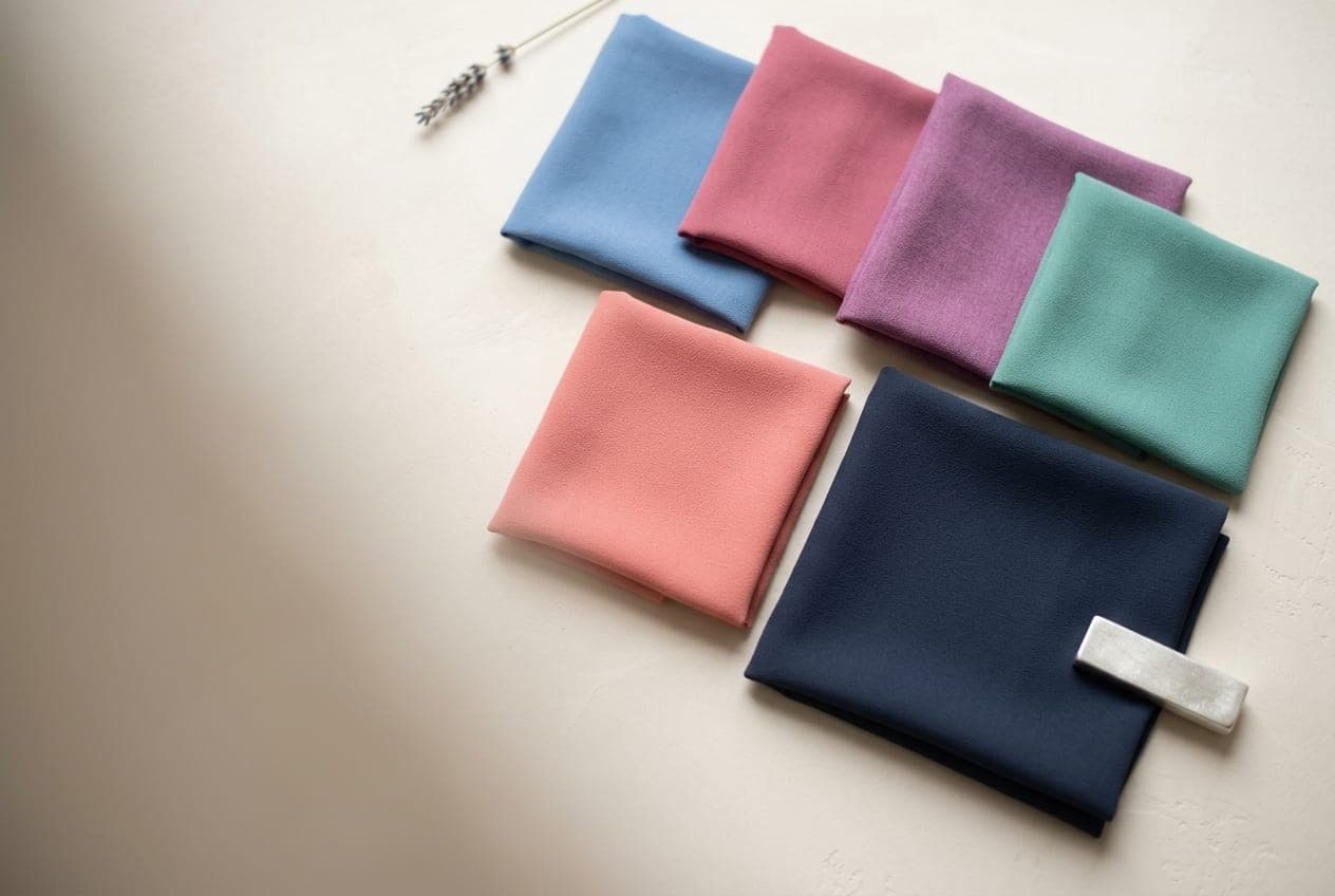 Folded squares of fabric in the True Summer palette, with its best neutral and metal