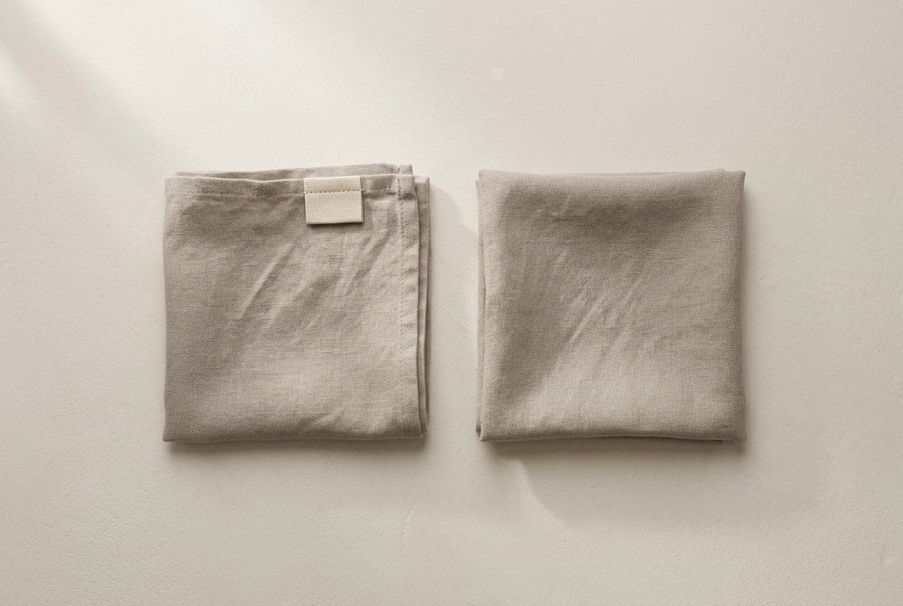 Two identical cloth squares, one carrying a blank woven label tab and one with none
