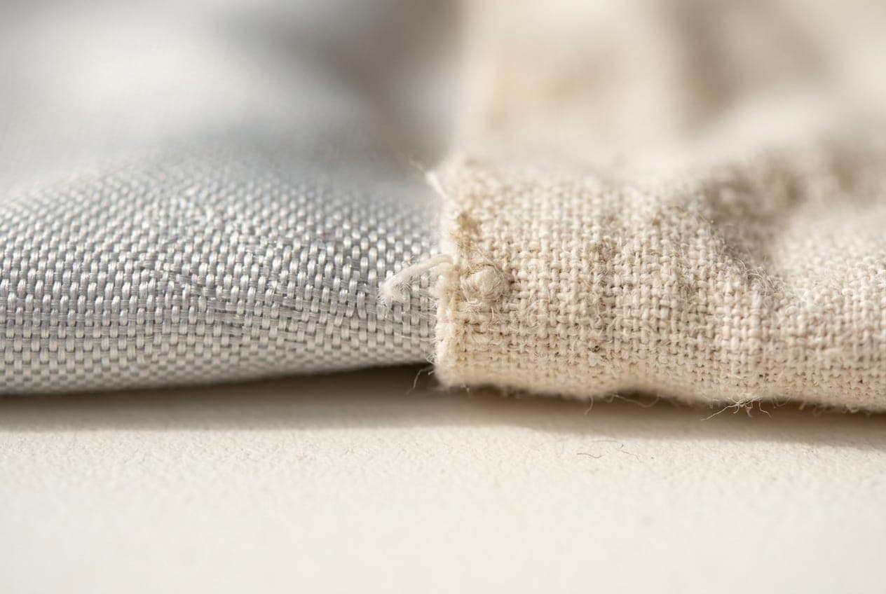 A macro of a smooth synthetic weave meeting a slubby matte cotton